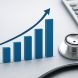 A 3D bar graph showing growth next to a stethoscope and calculator on a grid background.